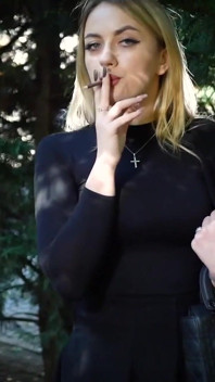 Gagică blondă sexy care fumează două țigări negre în natură