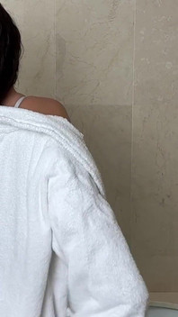 Zralá žena se v koupelně svléká kromě podprsenky