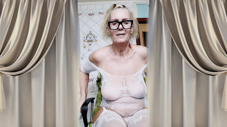 Lukerya: Glad hemmafru Lukerya Flörtar i en öppen, transparent vit jumpsuit i...