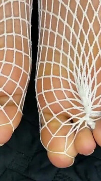 Zwart meisje pronkt met haar voeten met Franse pedicure in haar blanke visnetten