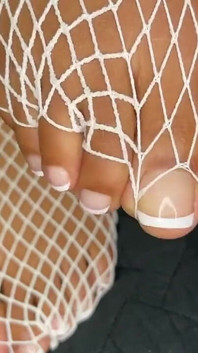 Ébano menina mostra seus pés com pedicure francês em suas meias brancas