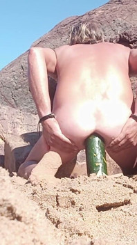 Una Persona Joven Se Separa Los Glúteos En La Playa Mientras Otros Observan.