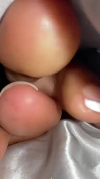 Chica de ébano debajo de sus cubre en la cama muestra los pies