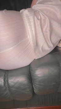 Furzen im weißen Satin-schlafanzug auf grünem Leder sofa