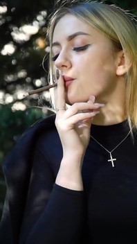 Calda bionda che fuma due sigarette nere in natura