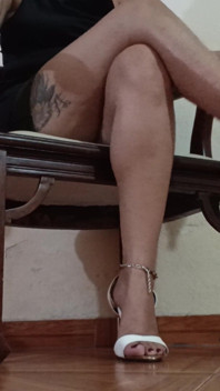 Grande a gambe incrociate e in piedi, tacchi alti che pendono mentre beve un caffè delizioso