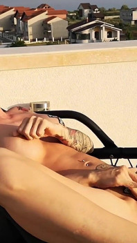 Une déesse excitée se masturbe sur la terrasse