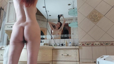A Charming Woman Is Preening in the Bathroom in Front of a Mirror