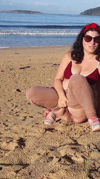 誰もいない公共のビーチで小便をする女性