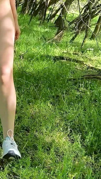 Piękna kobieta rozbiera się i chodzenie nago z pompą do łechtaczki na zewnątrz w publicznym lesie
