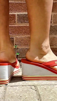 Pequeños pies asiáticos en chanclas de tacón rojo