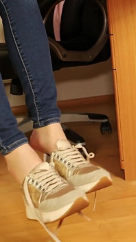 Beige sneakers en pure nylons - voetenspel en bungelend onder het bureau