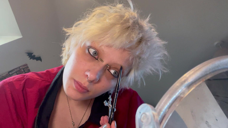 Glitterqueen1999: Gotická dívka Glitterqueen1999 tě ignoruje, zatímco aplikuje svůj make-up, černá rtěnka,...