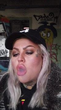 O doamnă blondă fumează o țigară electronică pe scară